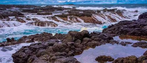 Un paysage côtier rocheux, avec une mer agitée dont les vagues déferlent avec force sur les rochers.