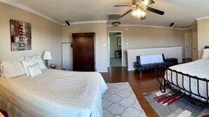 Ein Schlafzimmer mit zwei Betten, einem Deckenventilator, einer Uhr und einer Tür zu einem anderen Raum.