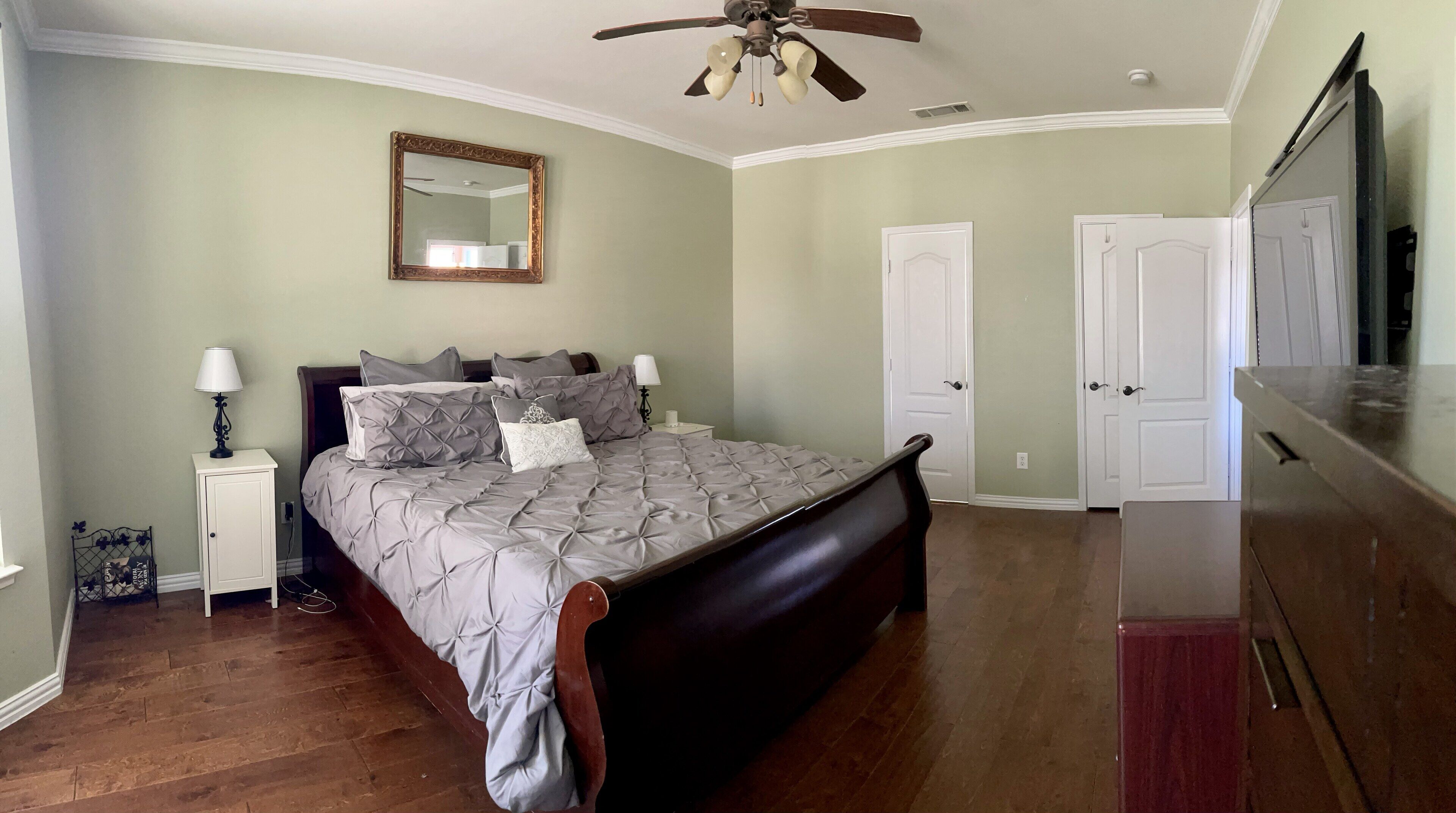 A bedroom with a bed, bedside tables, a ceiling fan, and a dresser.