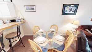 A dining area with a round glass table set for six, surrounded by wicker chairs.