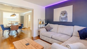 Ein modernes Wohnzimmer mit einer Couch, einem Couchtisch und einem Essbereich mit Stühlen und einem Tisch.