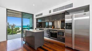 A modern kitchen with a large island, built-in appliances, and a view of the ocean. - OCEAN VIEWS @ NOR NOR EAST 201 (KINGSCLIFF)