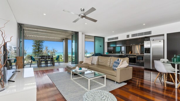 A modern living room with a glass coffee table, a beige sofa, and a view of the ocean. - OCEAN VIEWS @ NOR NOR EAST 201 (KINGSCLIFF)