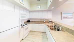 A modern kitchen with white cabinets, a stainless steel sink, and a microwave.
