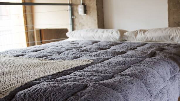 Una cama litera con una manta tejida y una escalera metálica.