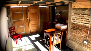 Una habitación con techo de madera, pared de ladrillo, una mesa de madera con sillas y una silla roja.