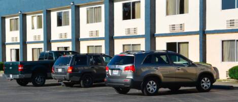 A row of multi-story motel buildings with several parked vehicles in front.