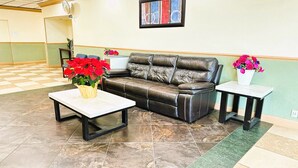 A lobby with a checkered floor, a leather sofa, a white table, and two flower vases. - Buckeye Inn Express (Columbus)