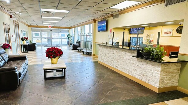 A reception area with a check-in counter, a leather couch, and a coffee table with flowers. - Buckeye Inn Express (Columbus)