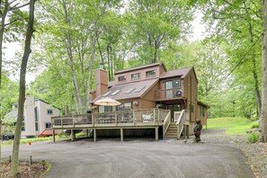 Une cabane en bois à deux étages, dotée d’une terrasse, d’une cheminée et d’une petite statue.