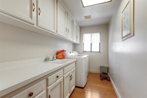 A laundry room with a washing machine, a dryer, and a sink with a bottle of detergent.