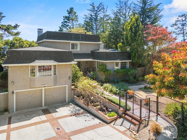 A two-story house with a garage, a landscaped garden, and a fenced driveway.