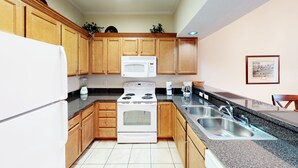 A kitchen with wooden cabinets, a white stove, a microwave, and a sink.