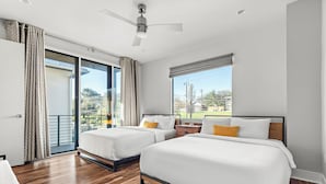 Een hotelkamer met twee bedden, een balkon en een plafondventilator.