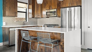 Een moderne keuken met houten kastjes, roestvrijstalen apparatuur en een centraal eiland met barkrukken.