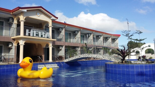 Um hotel com piscina, um flutuador de pato e uma ponte de pedra.