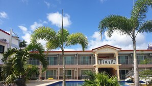 Hotel com piscina, palmeiras e uma placa com a inscrição 'HERALD'.