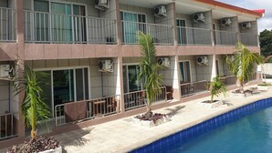 Um hotel com vários andares, varandas, aparelhos de ar condicionado e uma piscina.