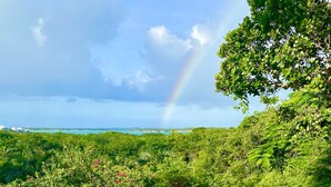 Une table dressée pour deux personnes, avec vue sur un paysage luxuriant et un arc-en-ciel.