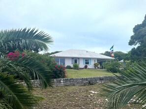 Una casa con un muro de piedra, un garaje y una bandera.