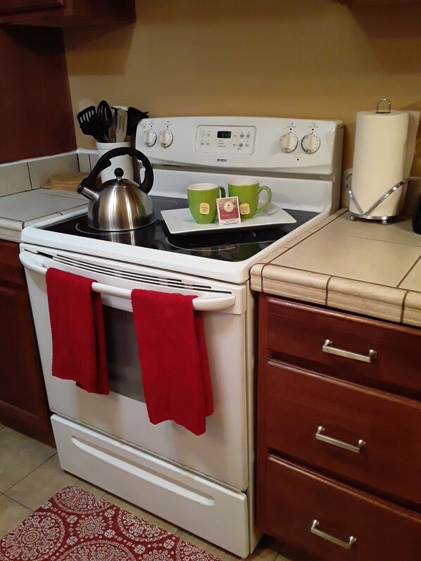 A kitchen with a stove, two green mugs, a kettle, and a red towel hanging on the oven handle. - House Perfect For Short/Long Term Stays! (Chewelah)