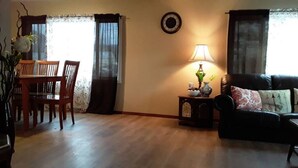 Ein Wohnzimmer mit Essbereich, einer Couch, einer Lampe und einer Wanduhr.