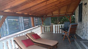 Un espacio de estar al aire libre cubierto con dos tumbonas, una mesa con sillas y vistas a la vegetación.