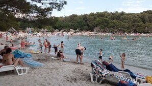 Una playa concurrida, gente nadando y tomando el sol.
