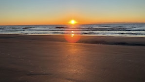 Uma praia com um pôr do sol sobre o oceano.