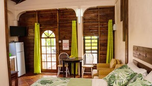 A room with a bed, a desk, a chair, a table with a bowl of fruit, and a sign instructing to sanitize hands. - Sunny Palm Villas (Laborie)