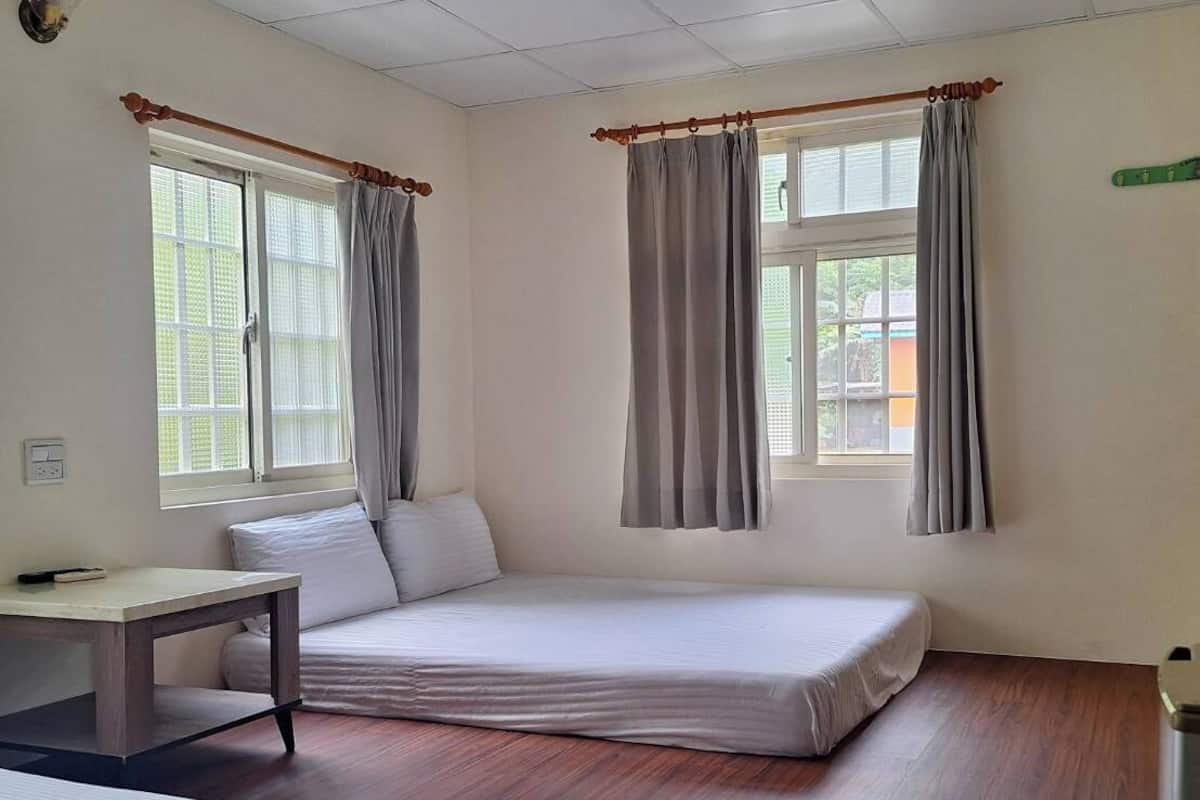 A room with two beds, a desk, and a window with curtains.