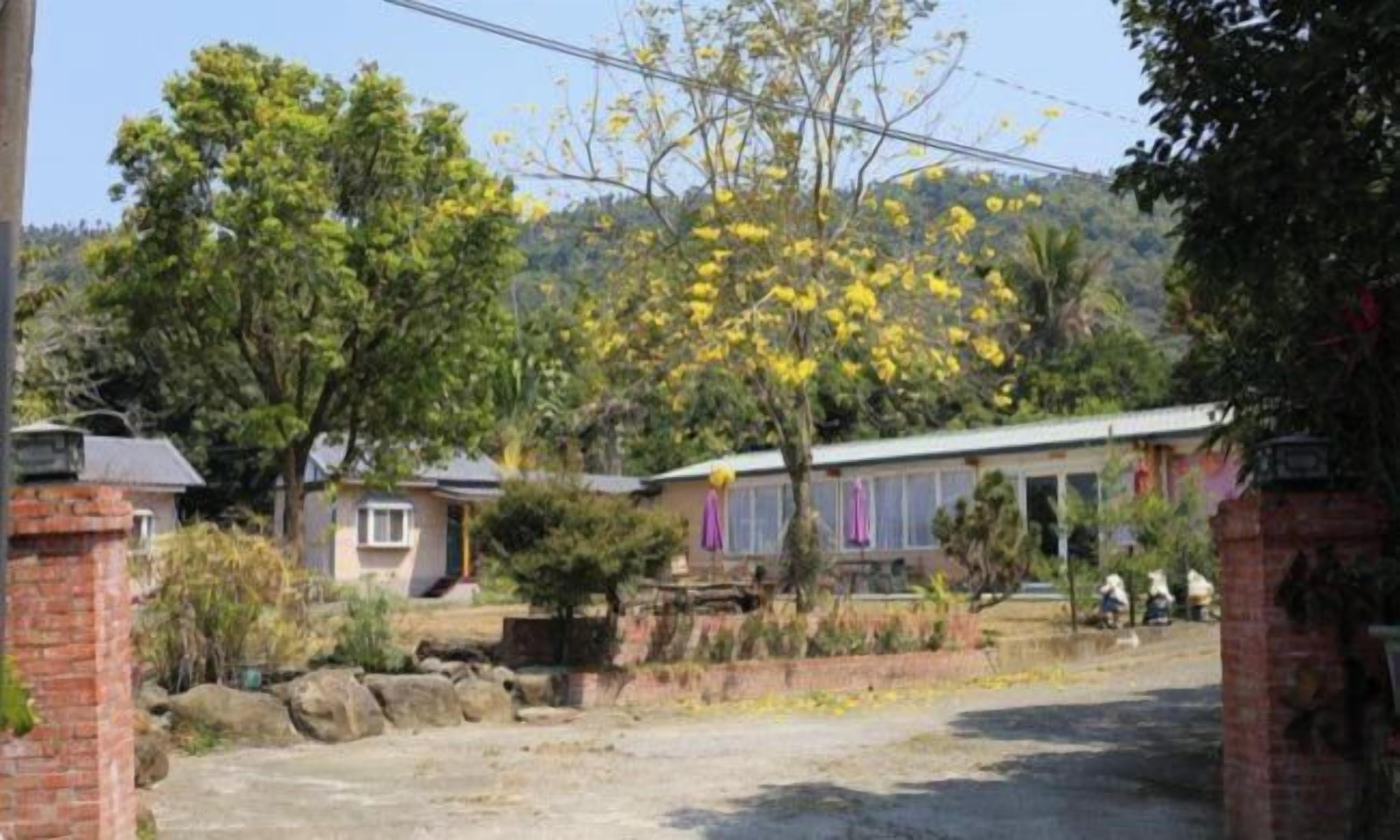 A residential area with houses, a paved driveway, and a hill in the background.