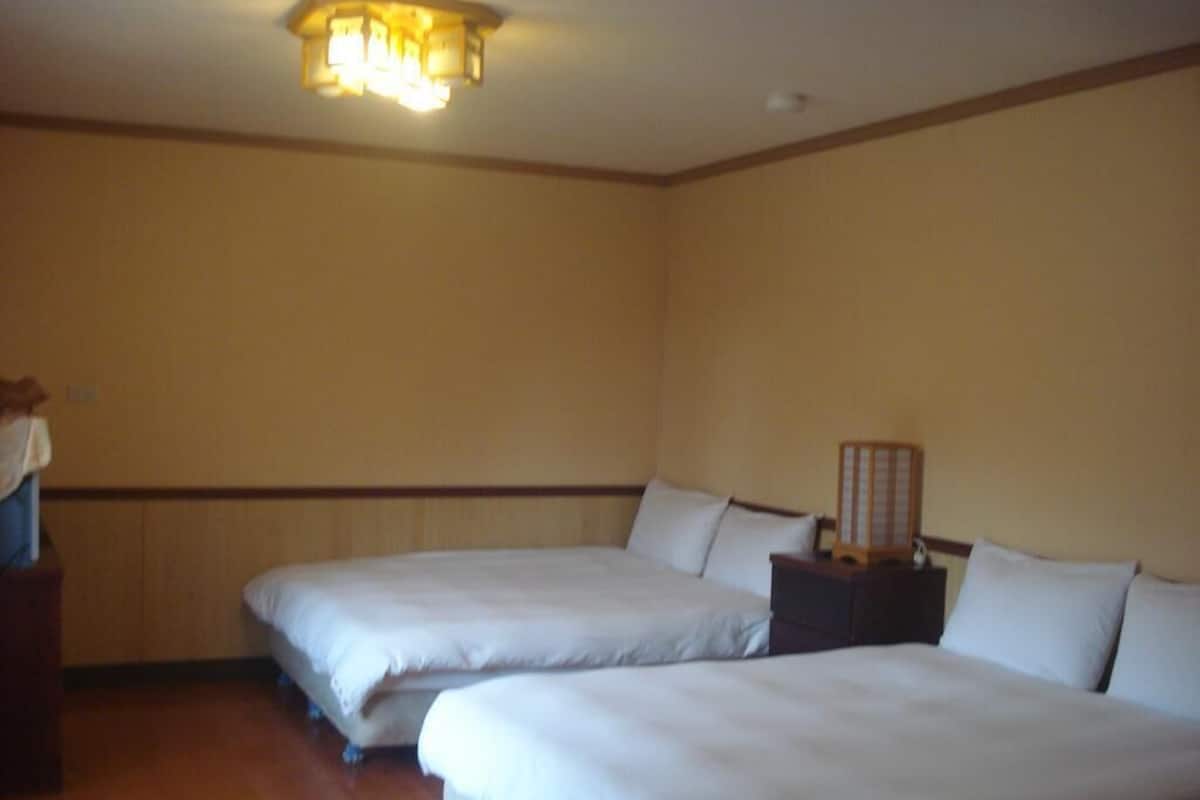A hotel room with two beds, a nightstand, and a ceiling light fixture.