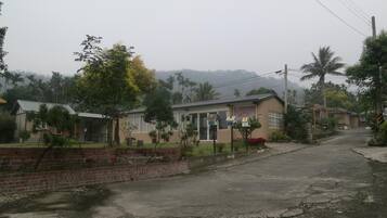 A residential street with houses, a paved road, and a brick wall.