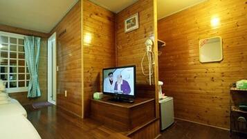 A wooden-paneled room with a television, a small table, and a chair.