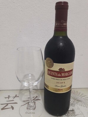A bottle of Quinta do Morgado wine next to an empty glass on a table with a white background. - Quartos em Maceio (Maceió)