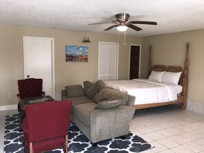 A bedroom with a bed, a red chair, a grey sofa, a ceiling fan, and a painting on the wall. - Freshly Renovated Studio with full kitchen, bathroom, and private gate, parking (Houston)
