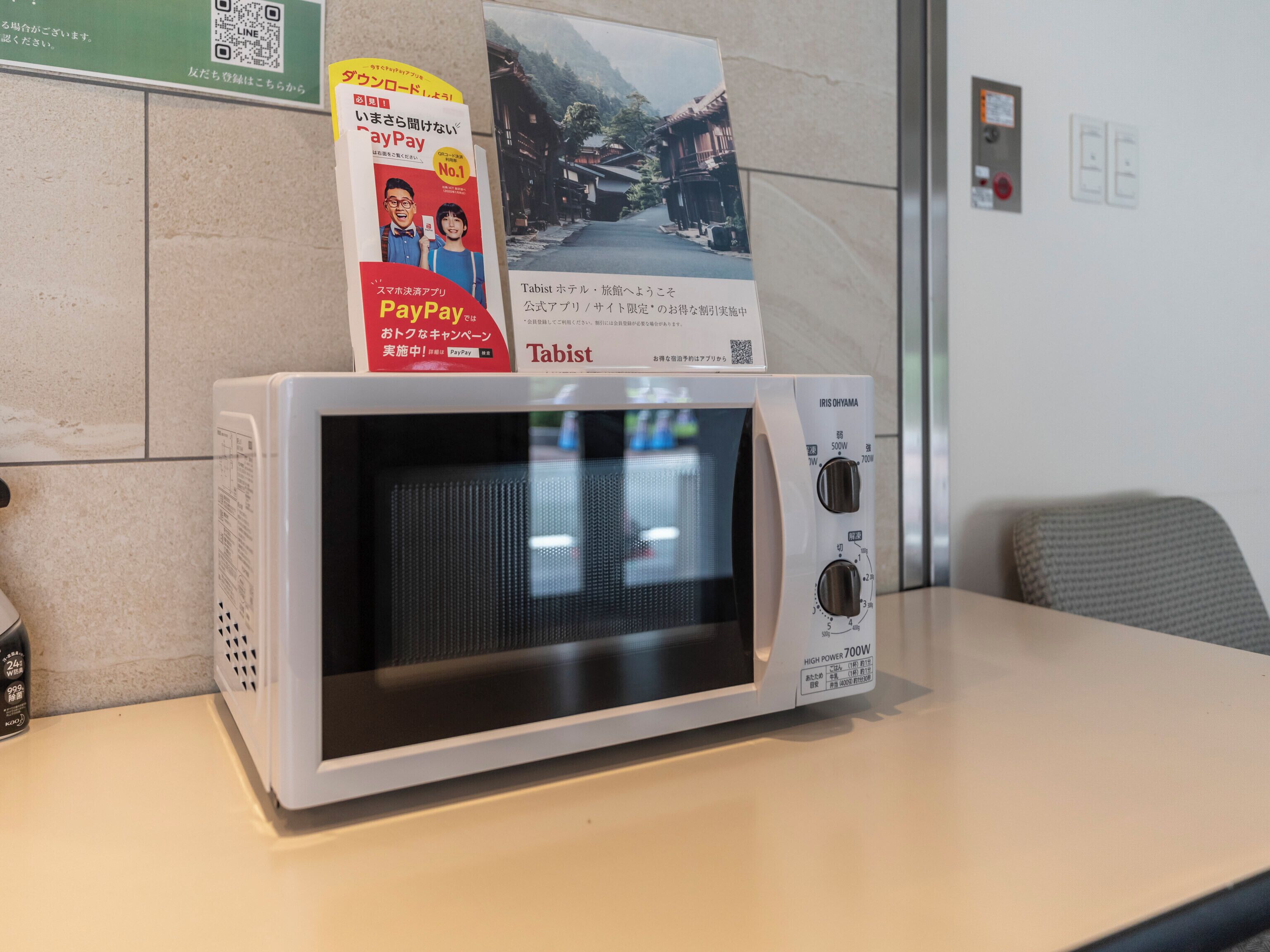 Un four à micro-ondes posé sur une table, avec une affiche et un code QR sur le dessus.