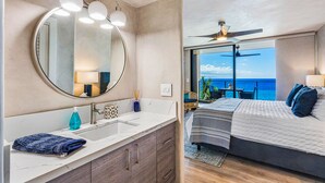 A bathroom with a large mirror, modern lighting, and a view of the ocean. - Luxury Mahana 1bd/2ba-Beautiful Remodel- Incredible Views-Free Parking/WiFi (Lahaina)