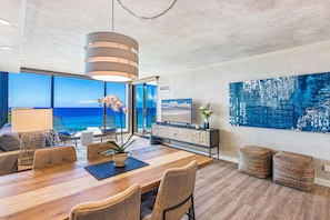 Enjoy ocean views from the spacious living area, featuring a large dining table and comfortable seating.