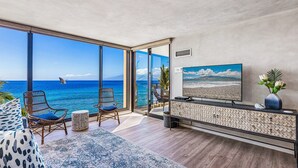 A balcony with a view of the ocean, wicker chairs, a TV, and a decorative vase. - Luxury Mahana 1bd/2ba-Beautiful Remodel- Incredible Views-Free Parking/WiFi (Lahaina)