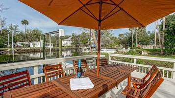 A wooden deck with a table and chairs, an umbrella, and a bottle of champagne.
