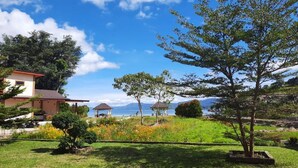 Un jardín con un porche, un árbol y vistas al mar.