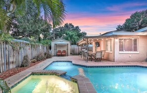 A backyard with a swimming pool, a covered patio area, and a fenced garden. - Fantastic Family/Friends Getaway - 6' deep Heated Pool & Spa close to Beaches! (Largo)