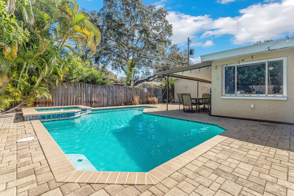 A backyard with a swimming pool, a wooden fence, and a covered patio area. - Fantastic Family/Friends Getaway - 6' deep Heated Pool & Spa close to Beaches! (Largo)