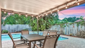 An outdoor patio with a pool, covered seating area, and string lights. - Fantastic Family/Friends Getaway - 6' deep Heated Pool & Spa close to Beaches! (Largo)