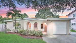 A two-story house with a stone facade, a garage, and a well-maintained lawn. - Fantastic Family/Friends Getaway - 6' deep Heated Pool & Spa close to Beaches! (Largo)