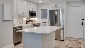 Una cocina moderna con armarios blancos, electrodomésticos de acero inoxidable y una isla central.