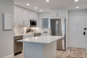 A modern kitchen with white cabinets, stainless steel appliances, and a central island.