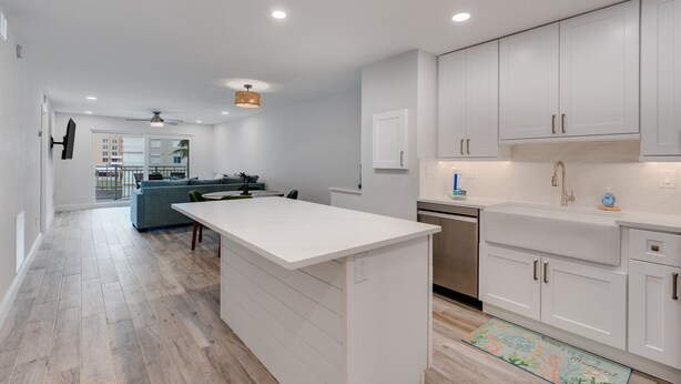 Una cocina moderna con armarios blancos, una isla central y un rincón comedor con sofá.